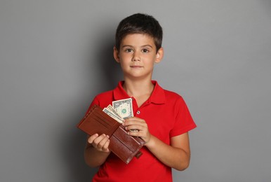 Cute boy with wallet and pocket money on grey background