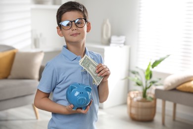 Cute boy with piggy bank and pocket money at home, space for text