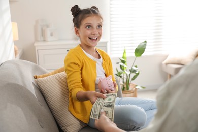 Photo of Mother giving pocket money to her daughter at home