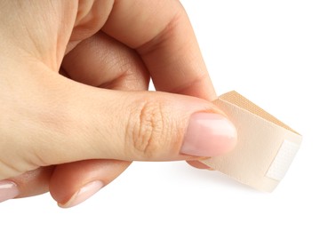 Photo of Woman putting medical adhesive bandage on white background, closeup