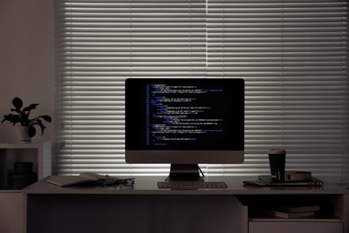 Programmer's workplace. Modern computer with unfinished code, coffee and supplies on desk