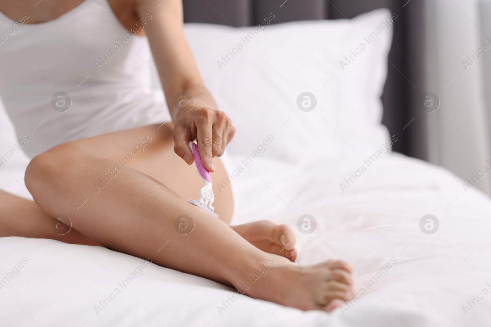 Photo of Woman shaving leg on bed, closeup. Depilation procedure