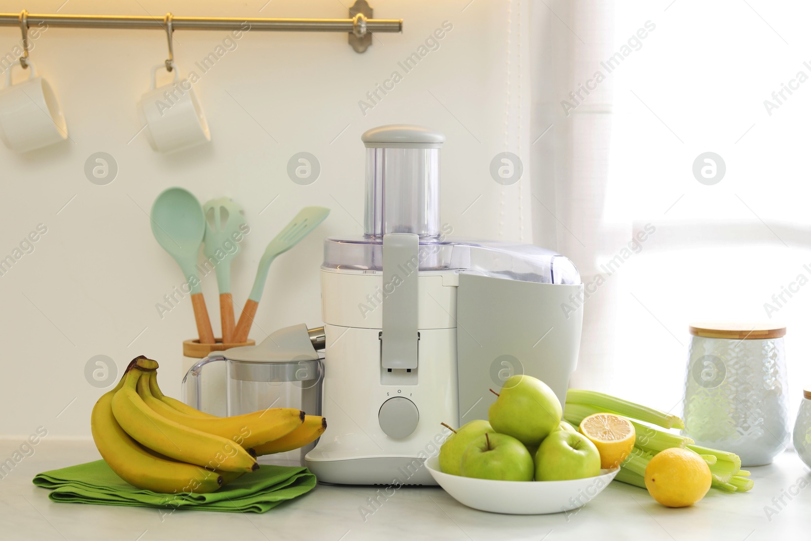 Photo of Modern juicer and fruits on white counter in kitchen