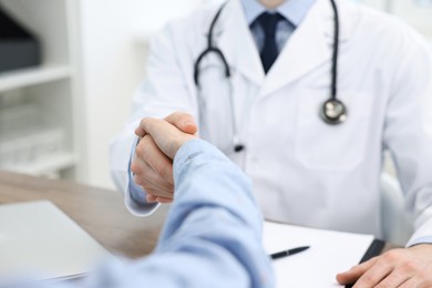 Doctor shaking hands with patient in clinic, closeup