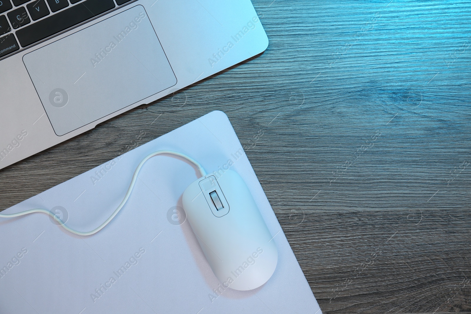 Photo of Computer mouse with mousepad and laptop on wooden table, flat lay. Space for text