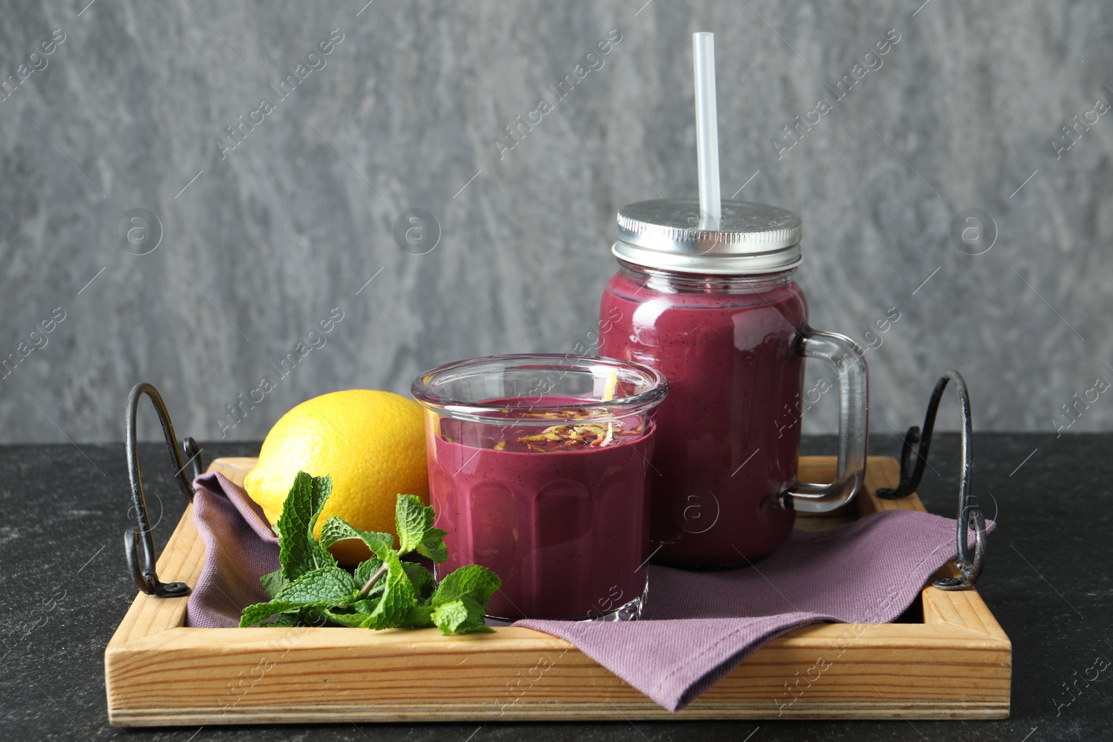 Photo of Tasty fresh acai juice with mint and lemon on grey table