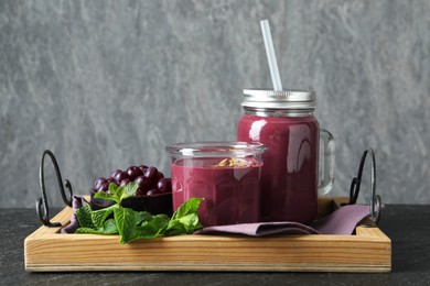 Tasty fresh acai juice with mint and berries on grey table