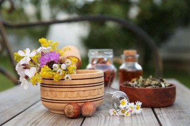 Photo of Different ingredients for tincture, mortar and pestle on wooden bench outdoors