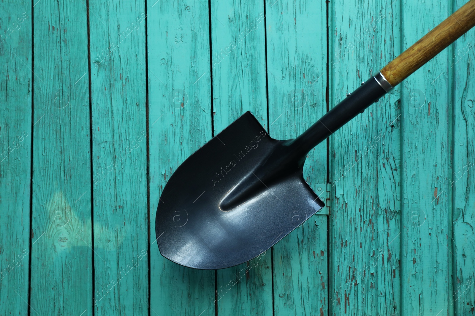 Photo of Metal shovel on turquoise wooden surface, top view