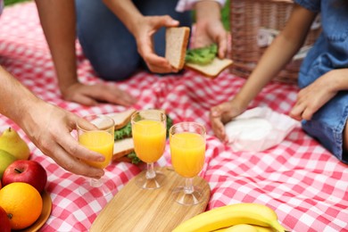 Family having picnic on checkered blanket outdoors, closeup