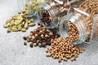 Photo of Different spices in glass jars on grey table, closeup