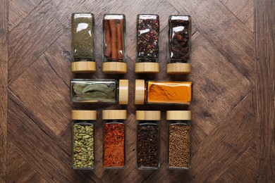 Photo of Different spices in glass jars on wooden table, flat lay