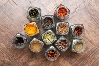 Photo of Different spices in glass jars on wooden table, flat lay