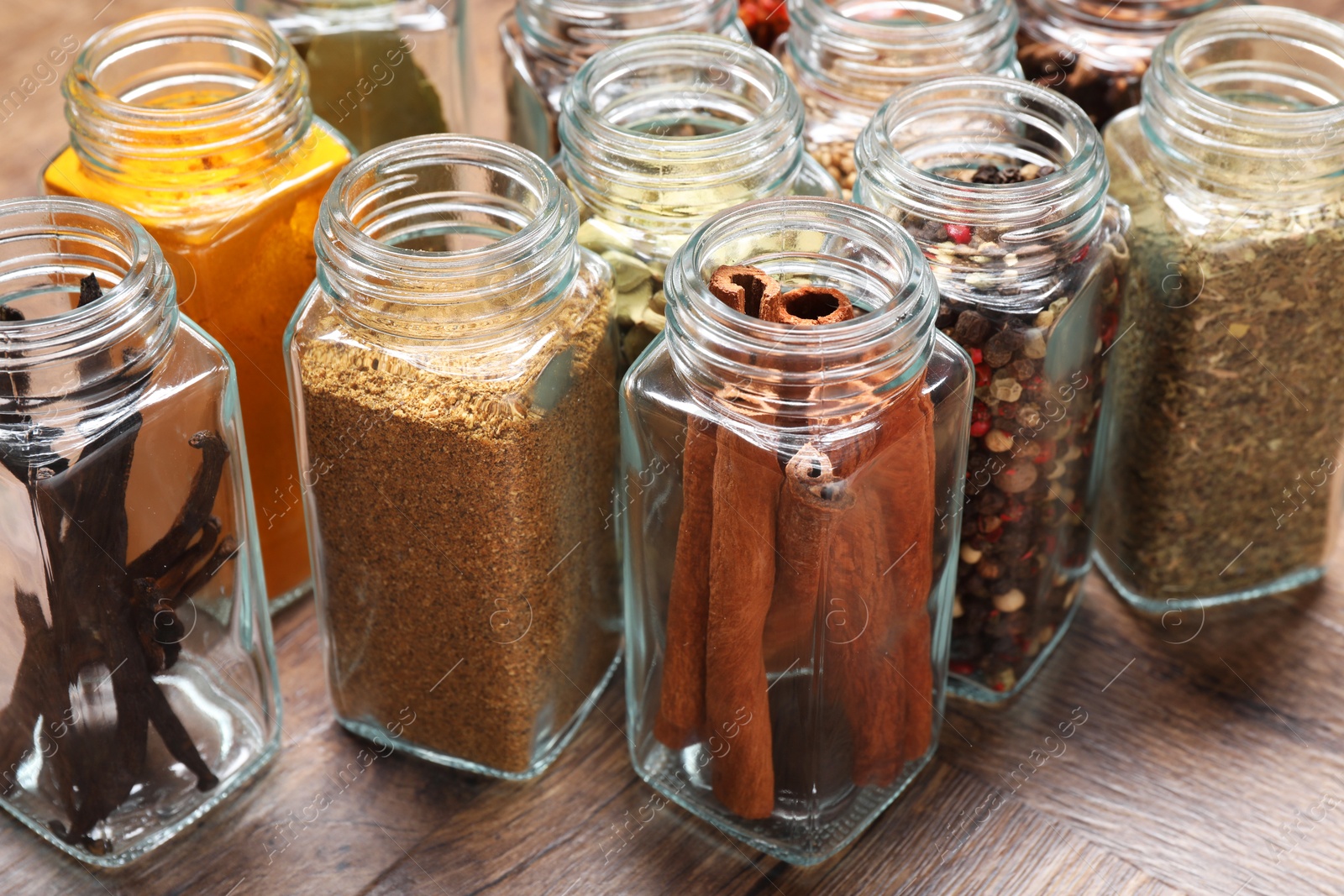 Photo of Different spices in glass jars on wooden table