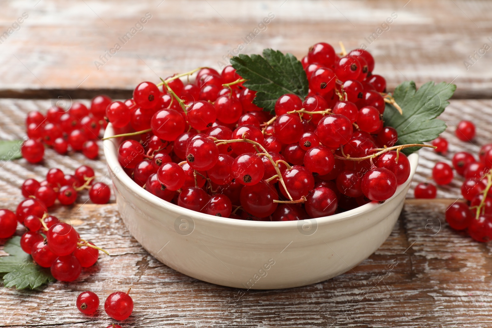 Photo of Fresh red currants in bowl on wooden table, closeup