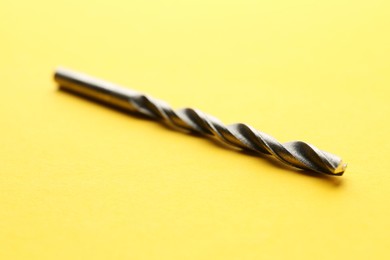 Photo of One drill bit on yellow background, closeup