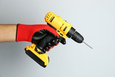 Photo of Man with cordless electric drill on light background, closeup