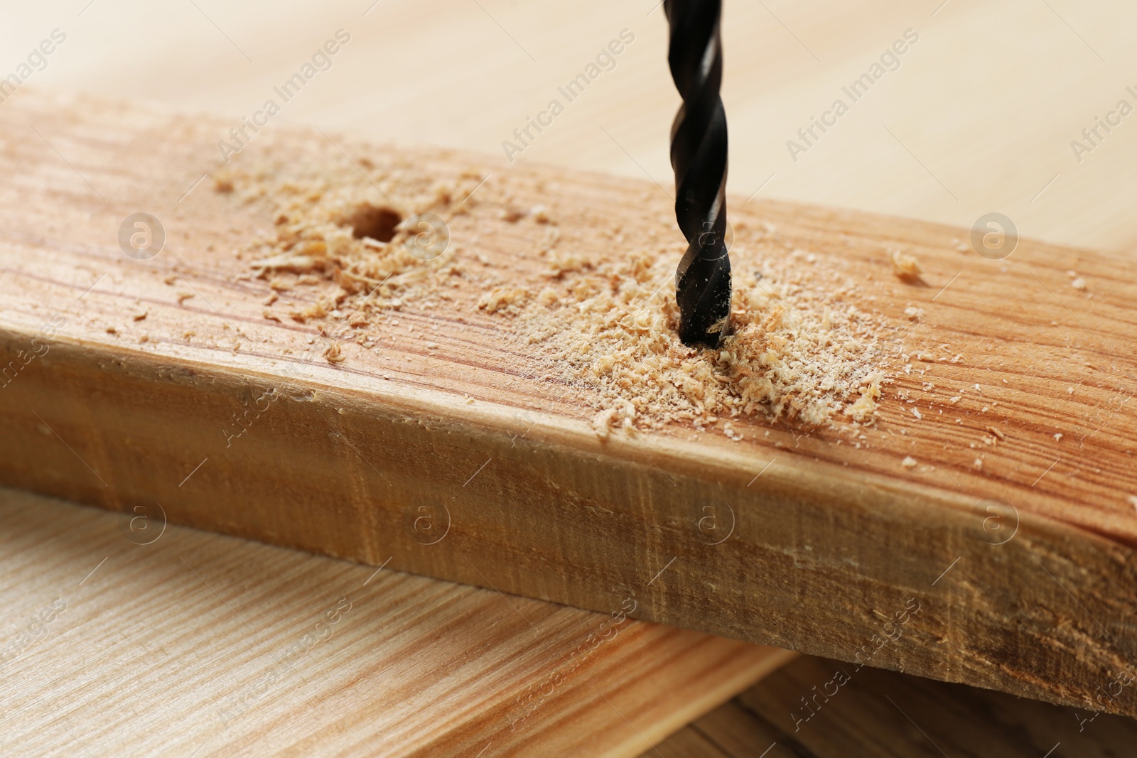 Photo of Drilling hole in plank on wooden table, closeup