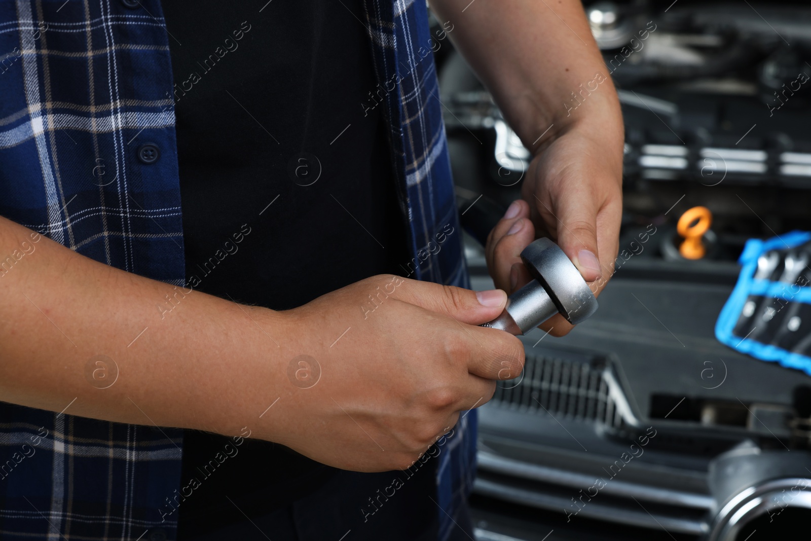 Photo of Auto mechanic with torque wrench at automobile repair shop, closeup