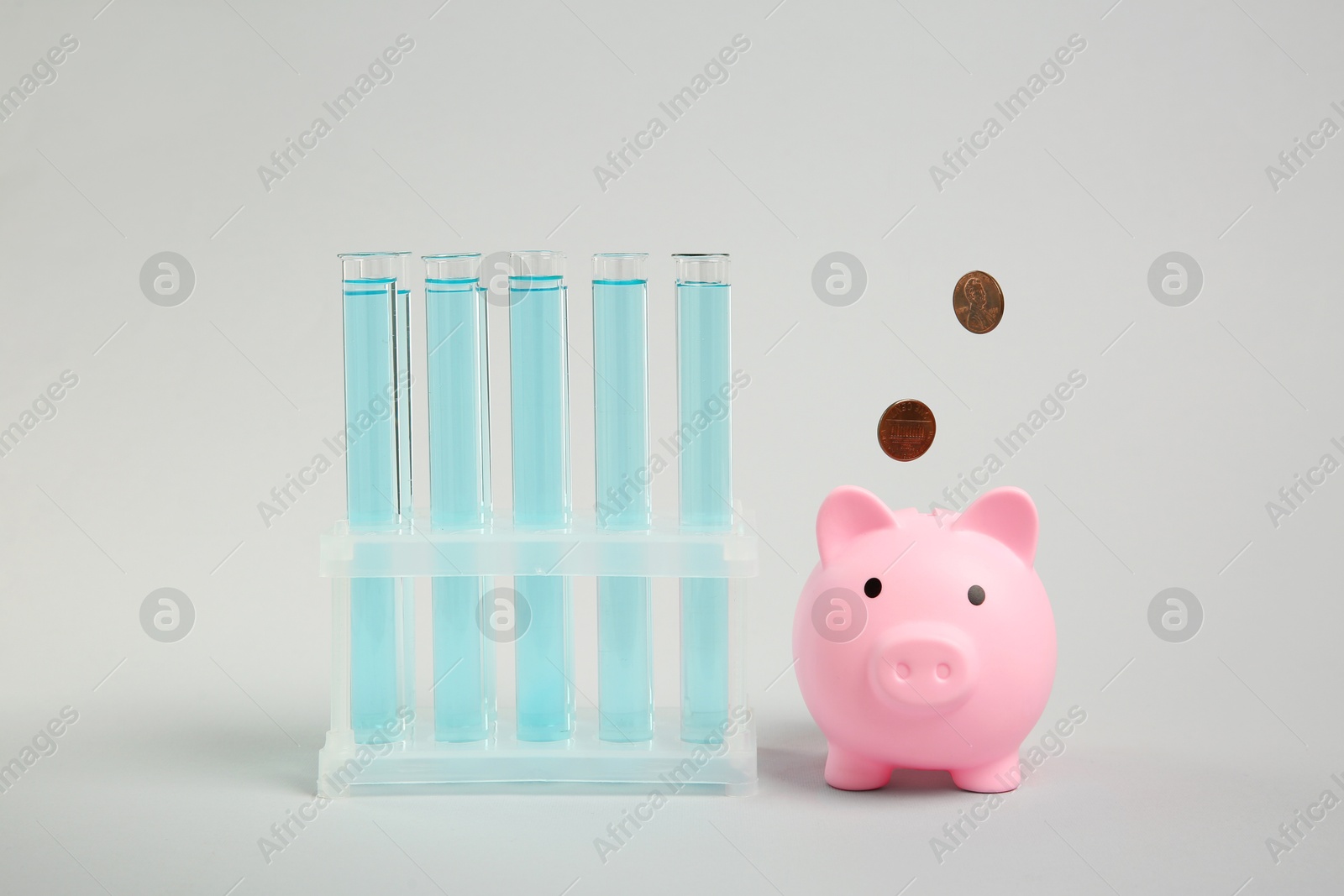 Photo of Water save concept. Piggy bank, coins and liquid in test tubes on light blue background