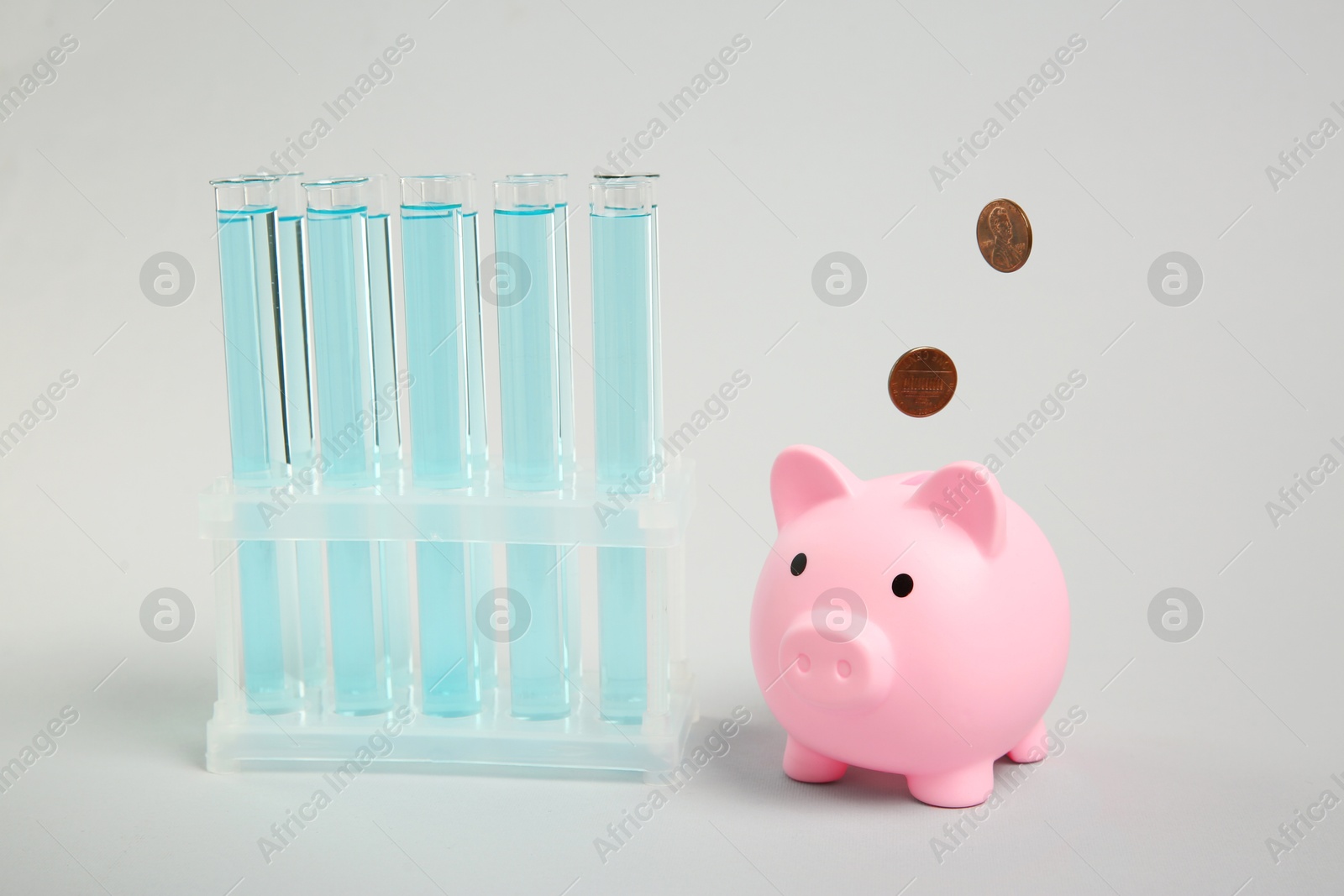 Photo of Water save concept. Piggy bank, coins and liquid in test tubes on light blue background