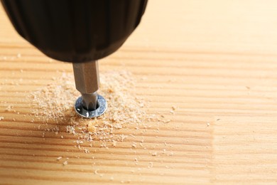 Photo of Screwing screw into wooden plank, closeup view