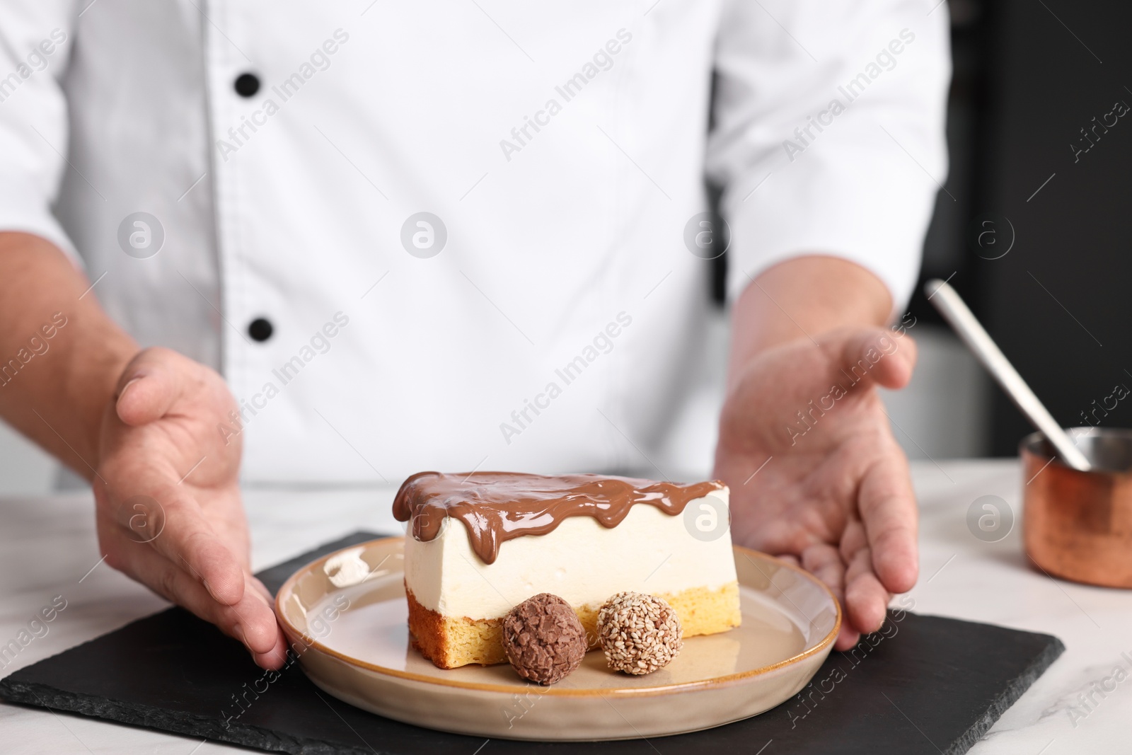 Photo of Professional chef with delicious cake at table in kitchen, closeup