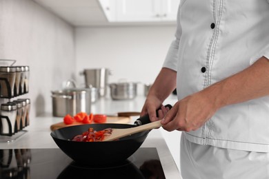 Photo of Professional chef cooking delicious food on stove in kitchen, closeup