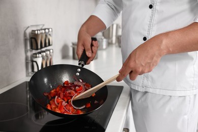 Photo of Professional chef cooking delicious food on stove in kitchen, closeup