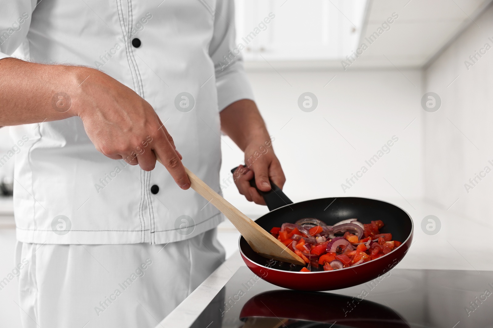 Photo of Professional chef cooking delicious food on stove in kitchen, closeup