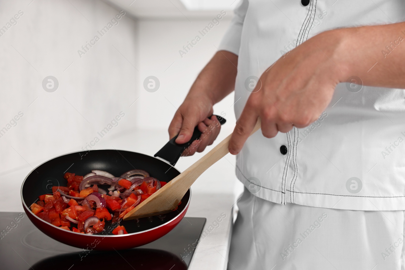 Photo of Professional chef cooking delicious food on stove in kitchen, closeup