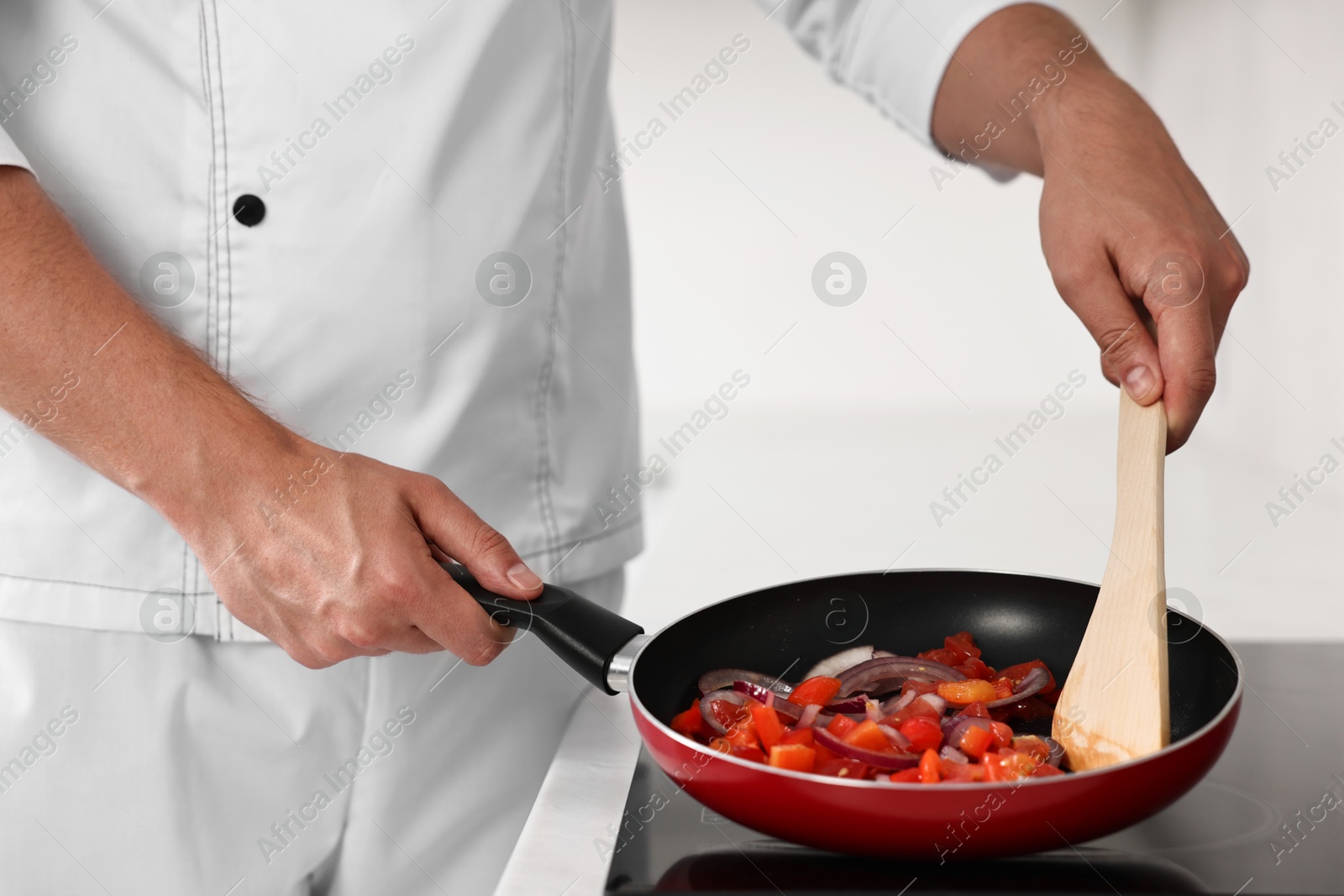 Photo of Professional chef cooking delicious food on stove in kitchen, closeup