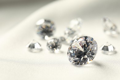 Many beautiful shiny diamonds on white fabric, closeup