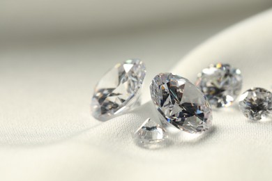 Photo of Many beautiful shiny diamonds on white fabric, closeup. Space for text