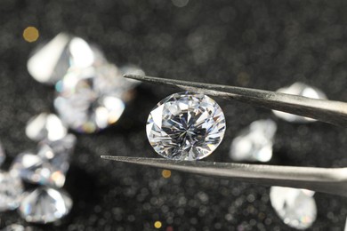 Photo of Tweezers with beautiful diamond on blurred background, closeup