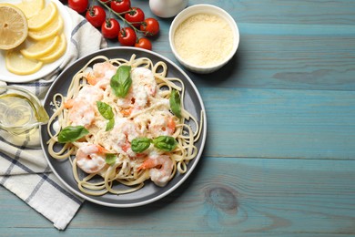 Photo of Tasty pasta with shrimps served on light blue wooden table, flat lay. Space for text