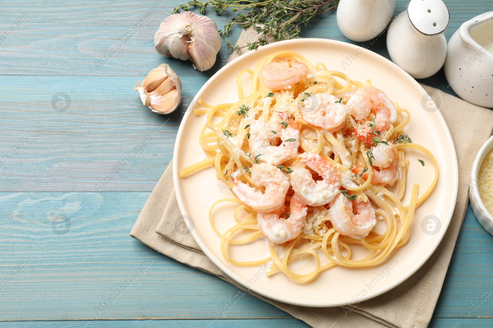 Photo of Delicious pasta with shrimps served on blue wooden table, flat lay