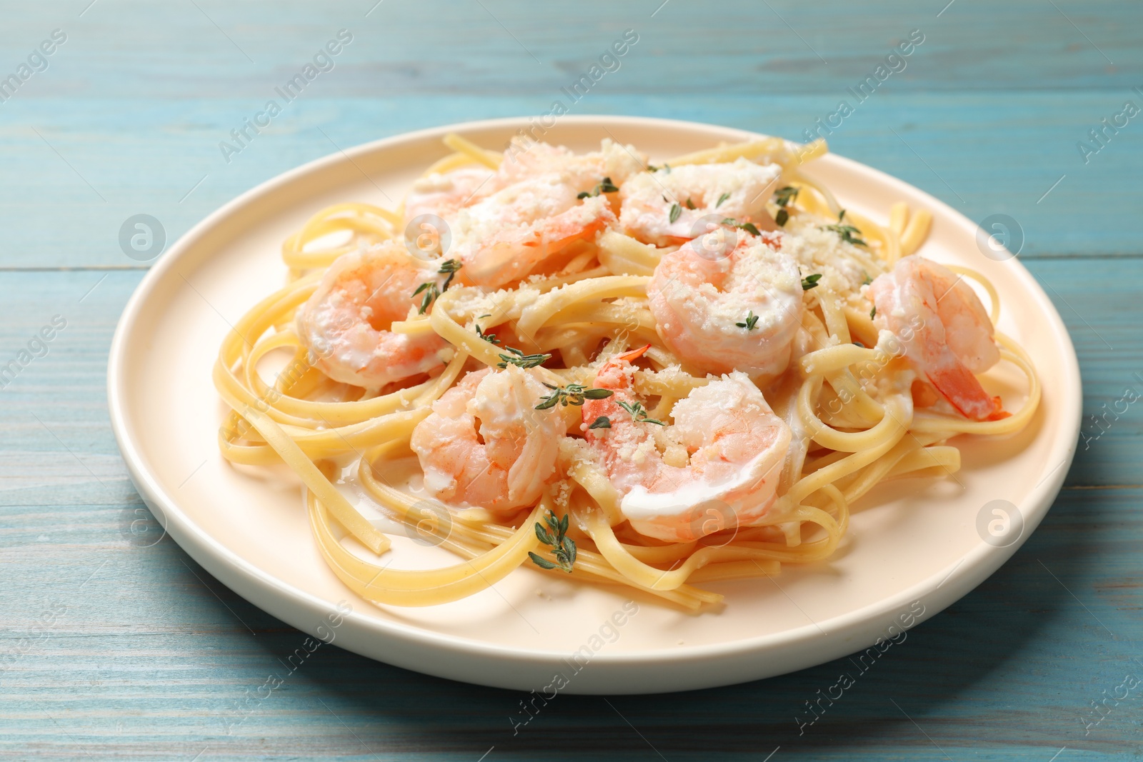 Photo of Delicious pasta with shrimps on blue wooden table, closeup