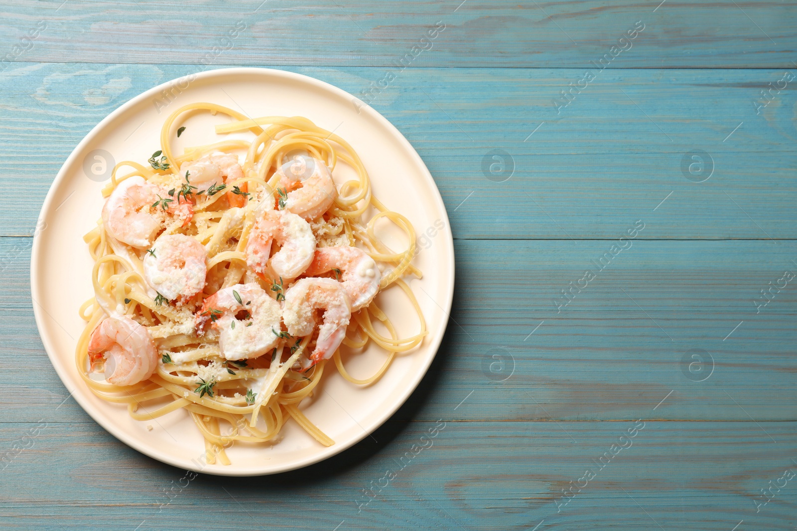 Photo of Delicious pasta with shrimps on blue wooden table, top view. Space for text