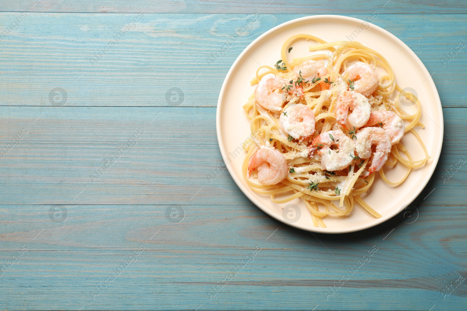 Photo of Delicious pasta with shrimps on blue wooden table, top view. Space for text