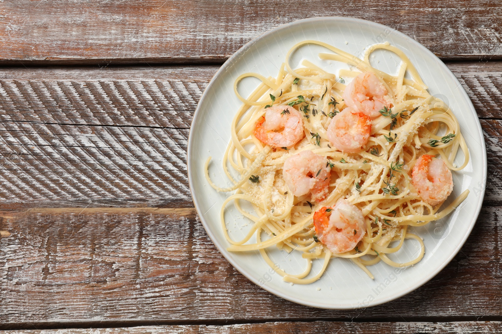 Photo of Delicious pasta with shrimps on wooden table, top view. Space for text