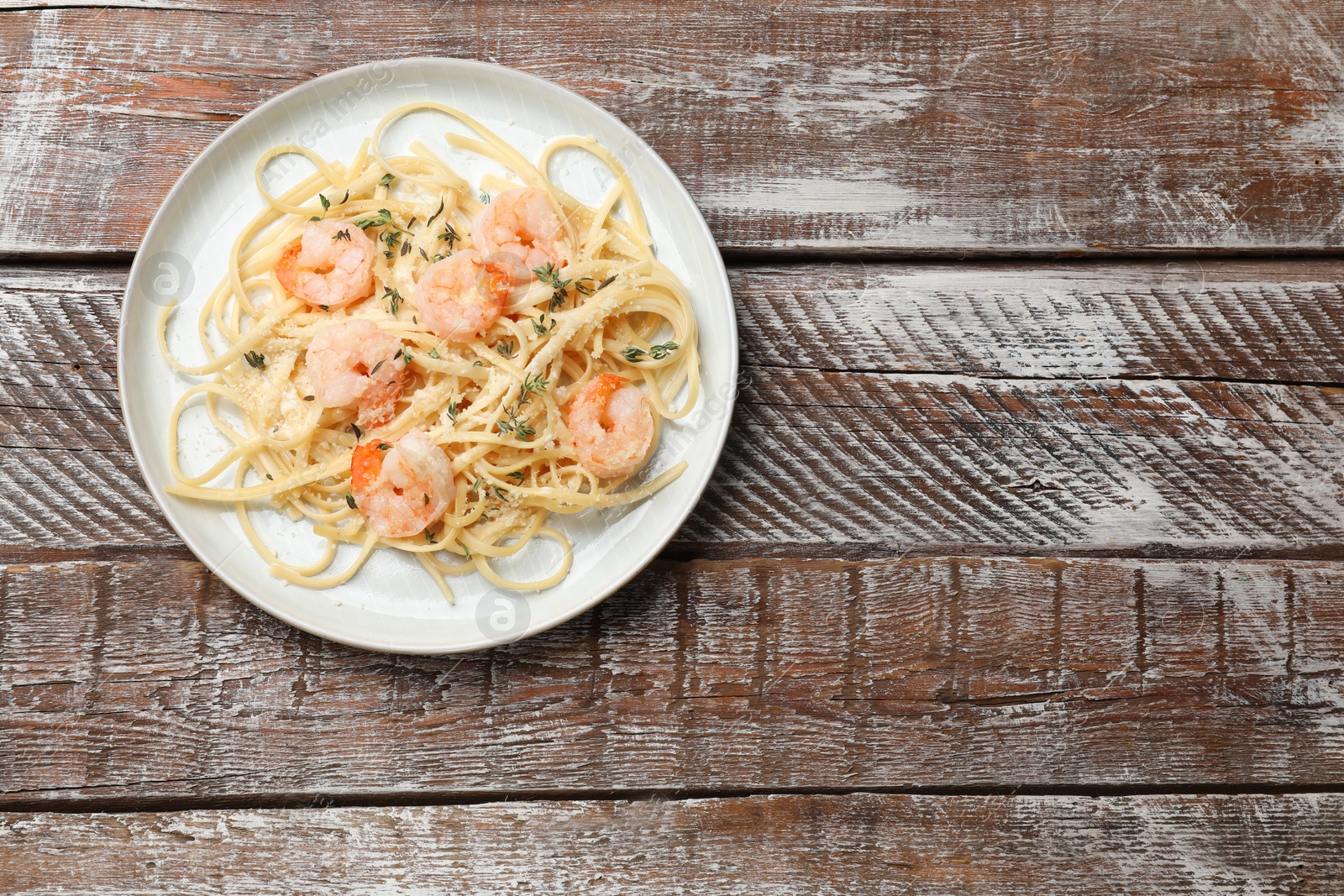 Photo of Delicious pasta with shrimps on wooden table, top view. Space for text