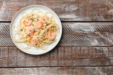 Photo of Delicious pasta with shrimps on wooden table, top view. Space for text