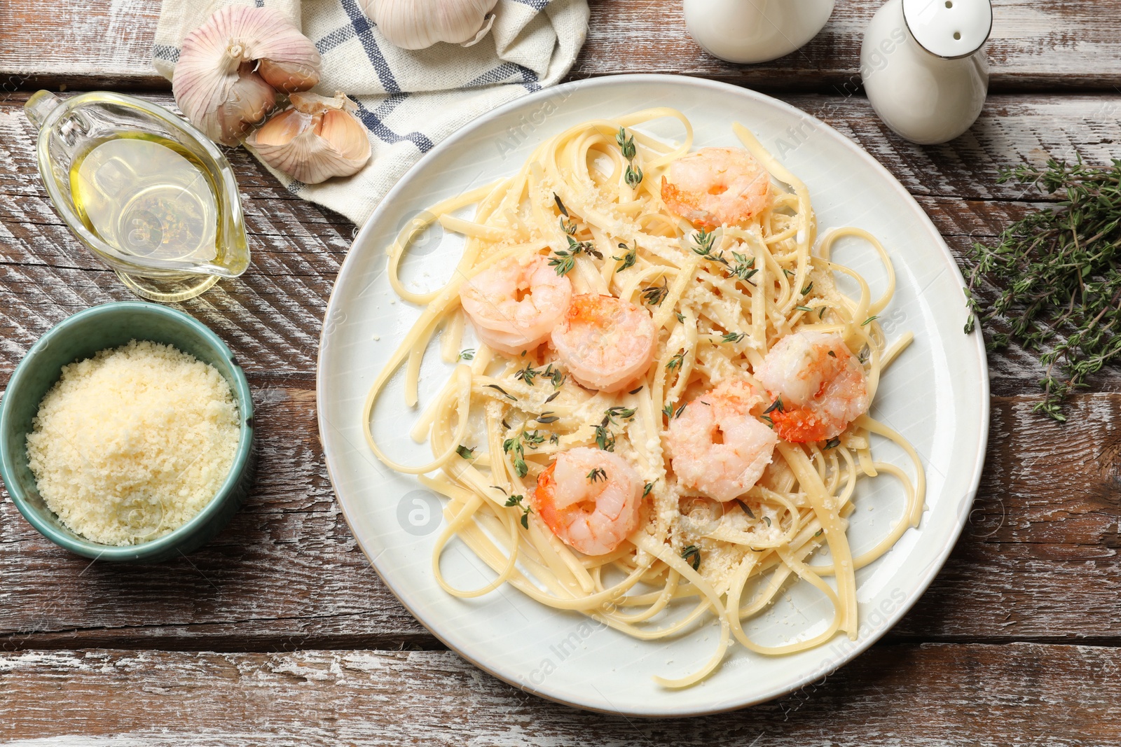 Photo of Delicious pasta with shrimps and products on wooden table, flat lay