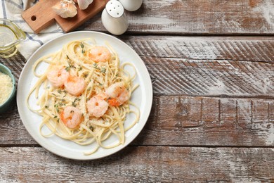 Photo of Delicious pasta with shrimps and products on wooden table, flat lay. Space for text