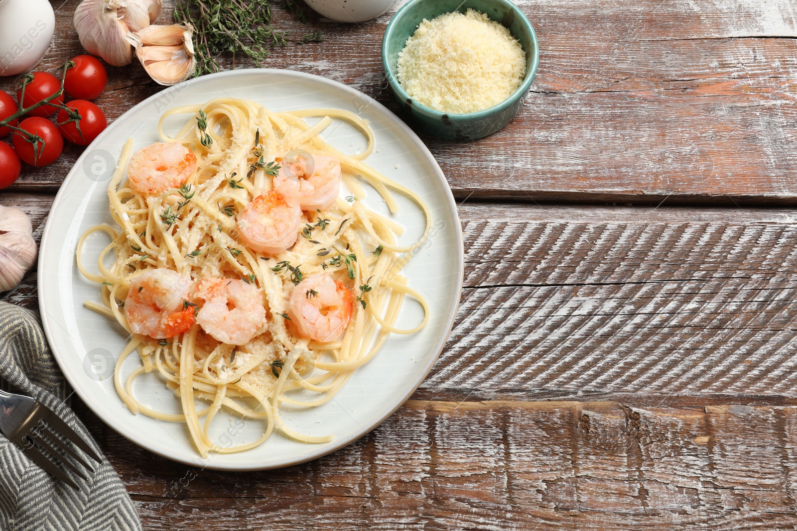 Photo of Delicious pasta with shrimps and products on wooden table, flat lay. Space for text