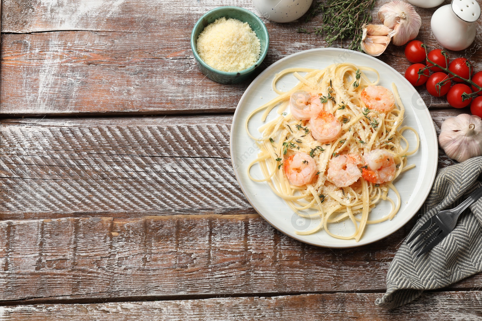 Photo of Delicious pasta with shrimps and products on wooden table, flat lay. Space for text