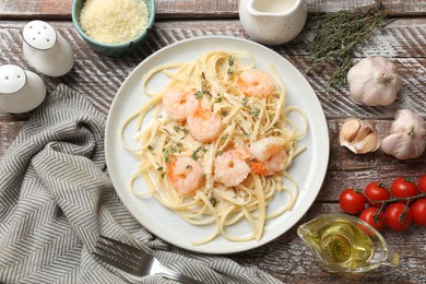 Photo of Delicious pasta with shrimps and products on wooden table, flat lay