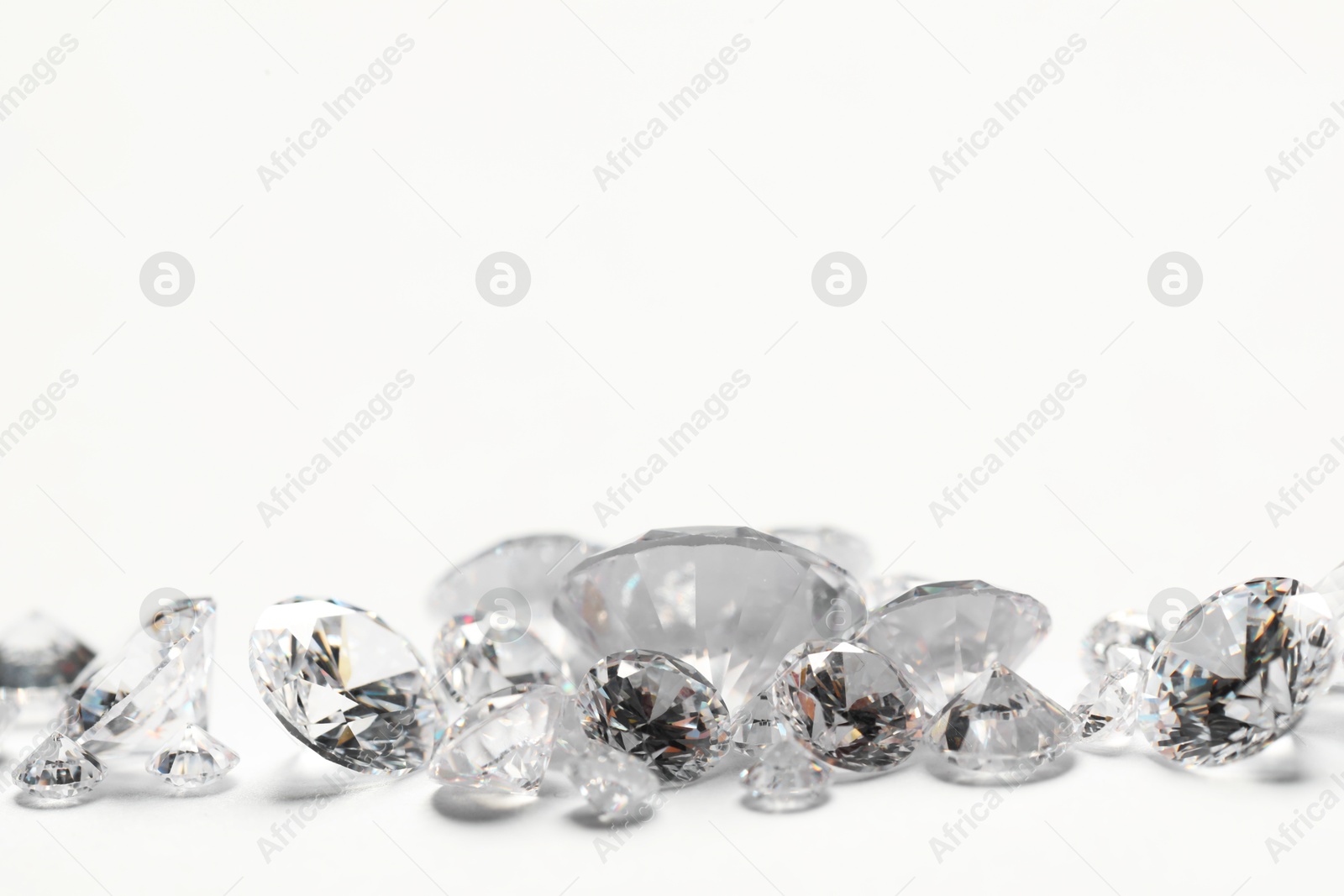 Photo of Many beautiful shiny diamonds on white background, closeup. Space for text