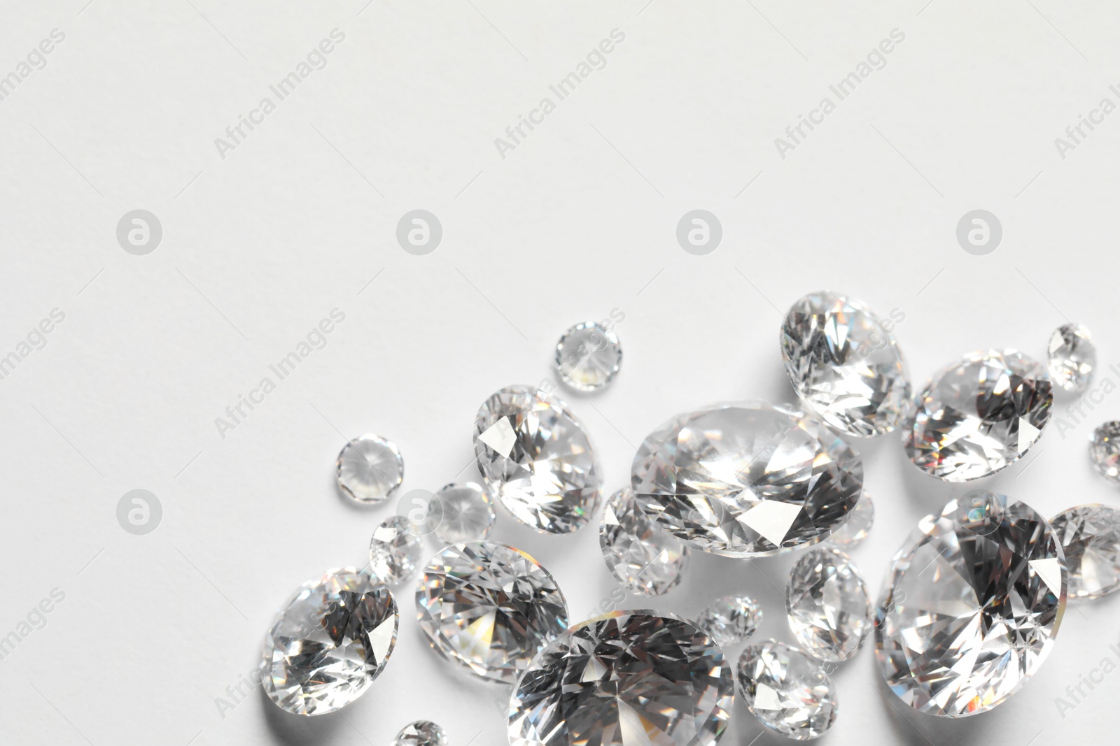 Photo of Many beautiful shiny diamonds on white background, flat lay. Space for text